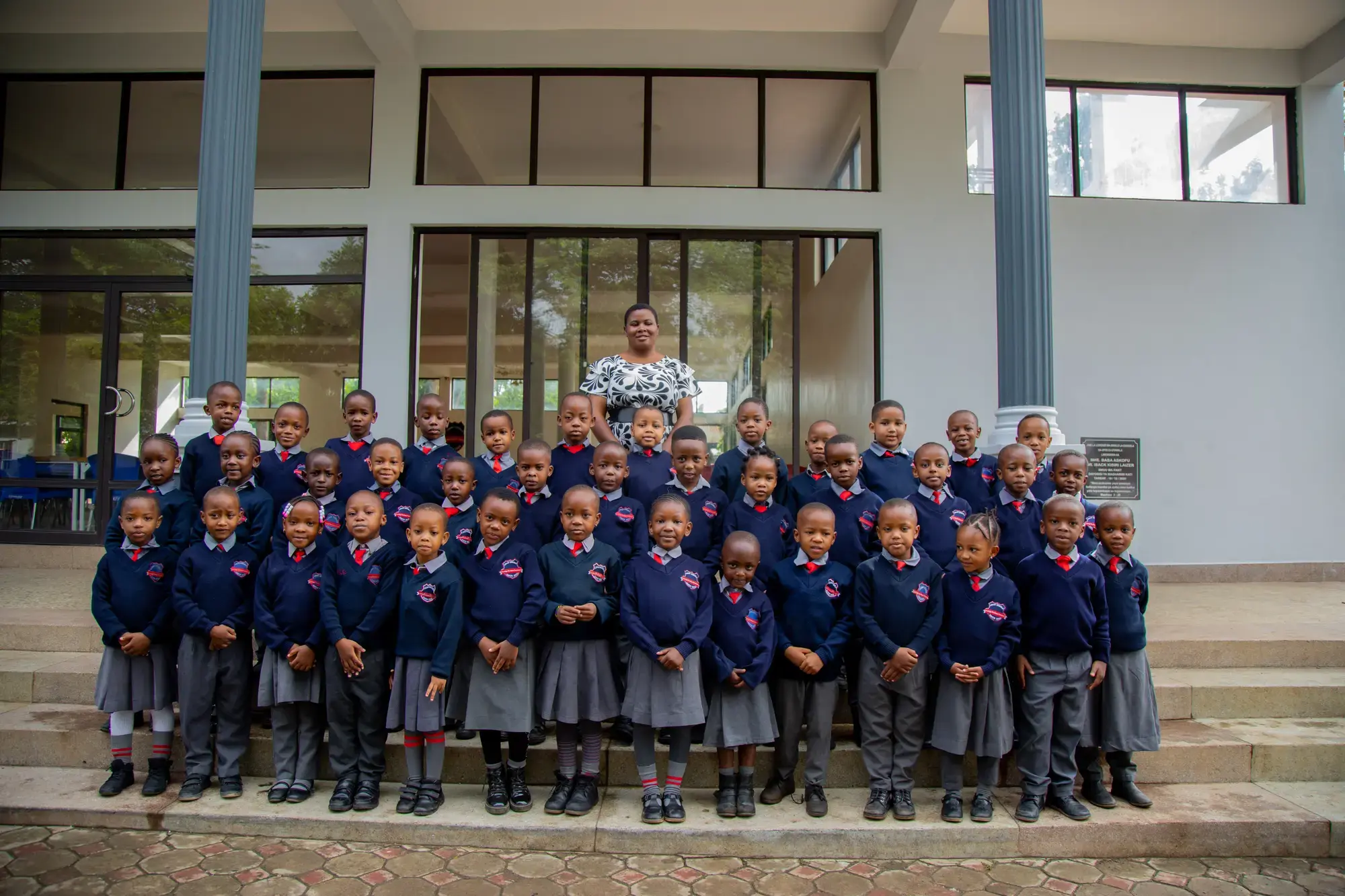 Loamo pupils in grey uniforms and red ties on the school steps